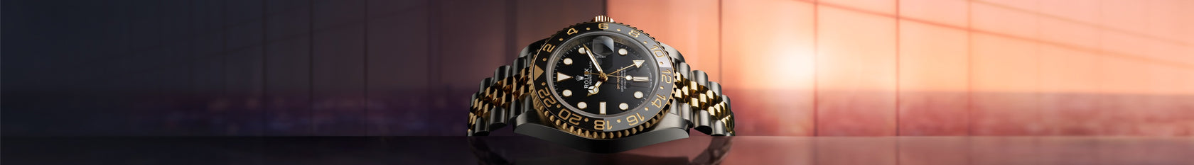 The Rolex GMT-Master II, ref 126713GRNR, lying on it's side with the sun in the background.