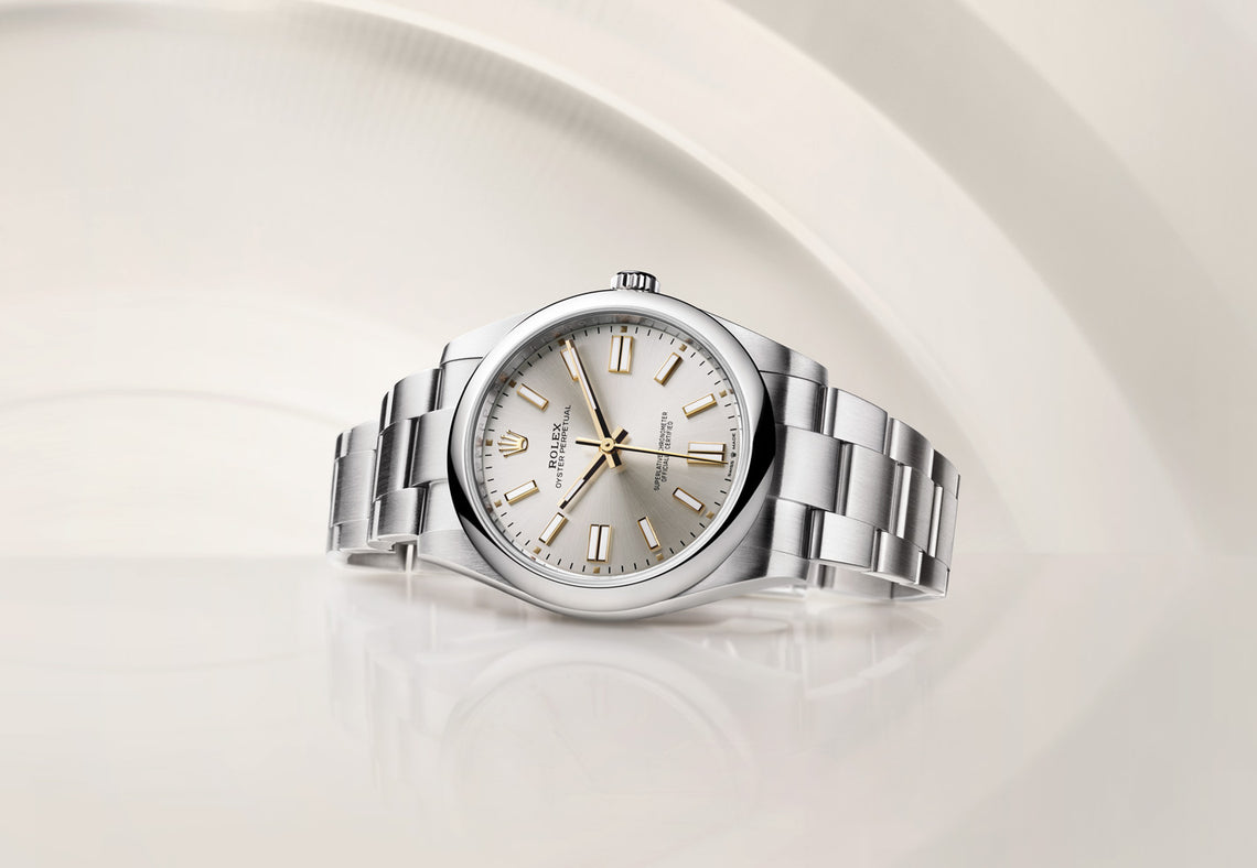 The Rolex Oyster Perpetual watch lying on its side. This watch is made from Rolex's Oystersteel and has a silver dial. Model #124300.