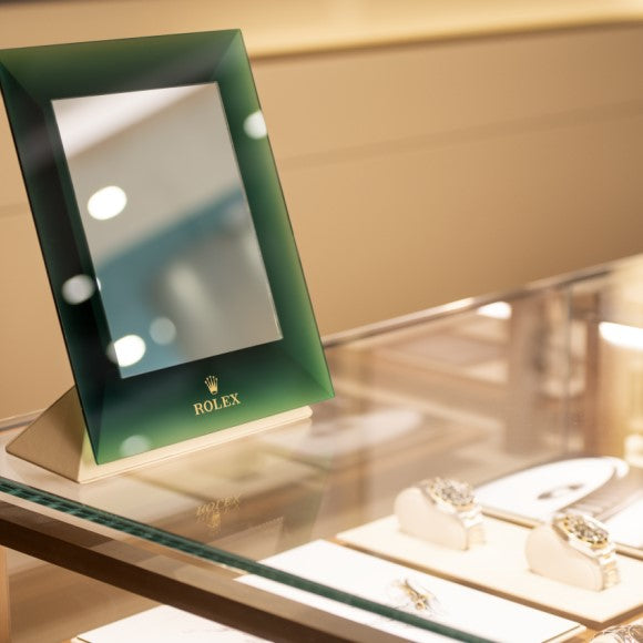 A green Rolex mirror sitting on top of our glass Rolex showcase.
