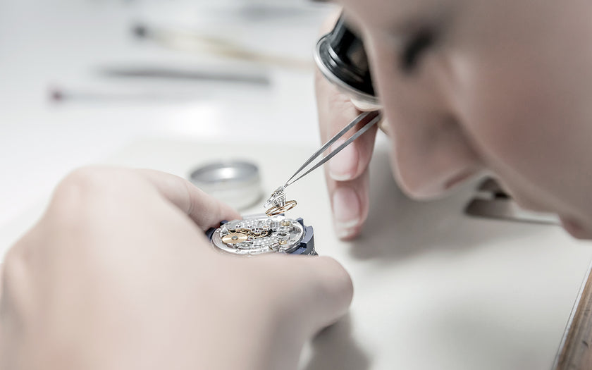 A Rolex technician wearing a loupe installing a parachrom hairspring into a Rolex movement.