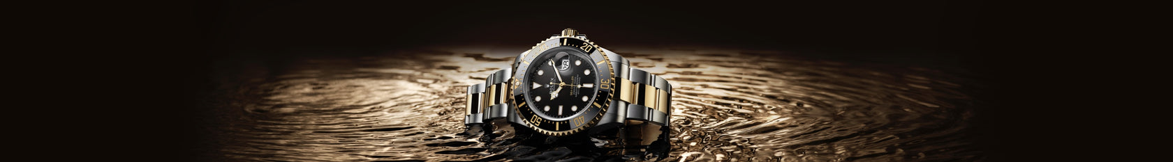 The Rolex Sea-Dweller in 18K yellow gold and Oystersteel lying in water with a golden hue. Model #126603.