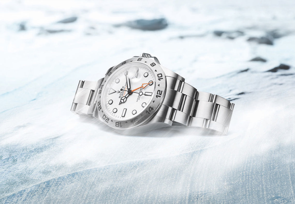 The Rolex Explorer II with a white dial in Oystersteel lying on its side on ice. Ref #226570.