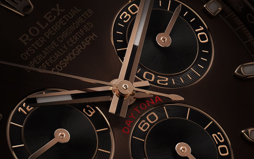 A close shot of the Rolex Cosmograph Daytona watch dial, showing the chronograph indicators and some of the writing on the chocolate dial.