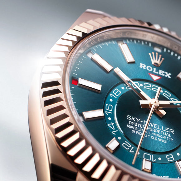 A cut off photo of the Rolex Sky-Dweller in 18K Everose gold with a blue-green dial. Ref #M336935-0001.