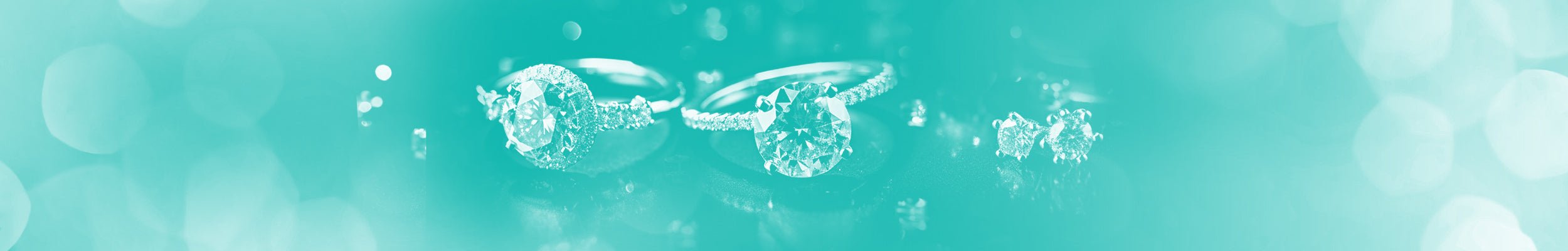 Rings and earrings lying on their sides on a teal background.