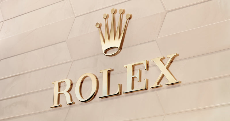 A close up shote of the Rolex logo on a patterned wall.