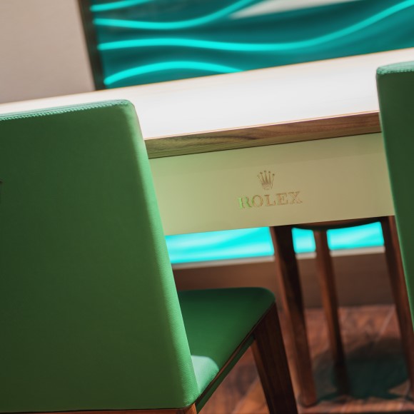Our Rolex desk with one of our green Rolex chairs pulled out for someone to sit in.