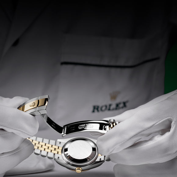 A white-gloved Rolex technician holding a Rolex Datejust 36 upside down looking at the caseback and clasp.