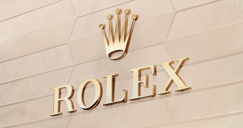 The Rolex logo in gold on a wall.