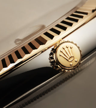 The Rolex crown logo on the crown of a Datejust watch in 18K yellow gold.